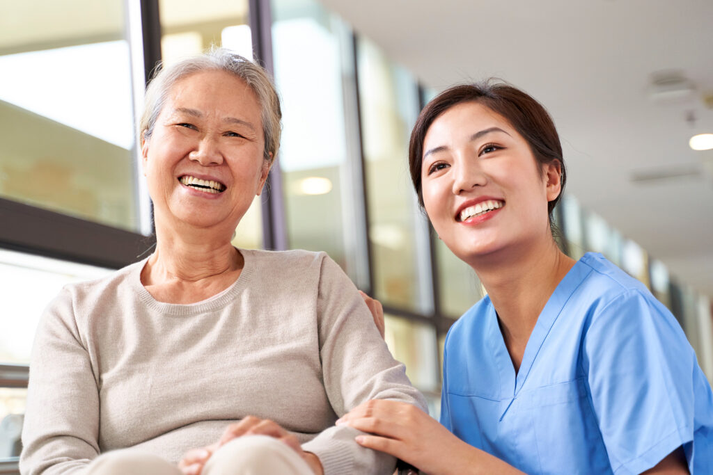 Asian,Senior,Woman,And,Her,Caregiver,Looking,At,Camera,Smiling
